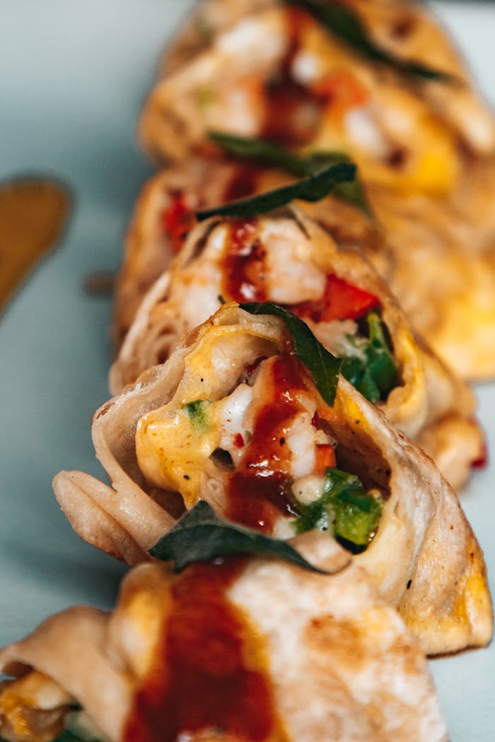 Close-up of tasty wraps filled with eggs, veggies, and sauce on a plate.